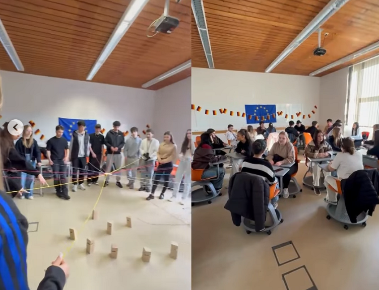 Austauschprojekt im Klassenraum: Gruppe arbeitet an einem Teamspiel mit gespannten Schnüren und Holzklötzen; rechts Gesprächsrunden an Tischen.