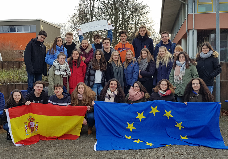 Gruppenbild: Jugendliche im Freien mit dicken Jacken an, die spanische und die europäische Flagge haltend. 