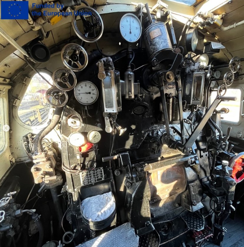 Blick ins Cockpit einer alten Lok. Oben links steht: ‘Funded by the European Union’ mit EU-Flagge.