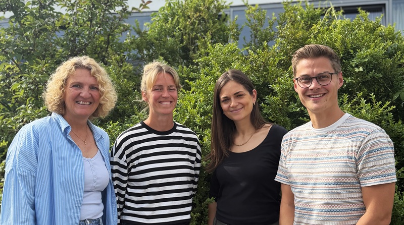 Ein Gruppenbild des Beratungsteams: Tanja Unrau, Nina Heckeroth, Viktoria Arndt und Jannes Heizmann, draussen in der Sonne vor einer Hecke. 