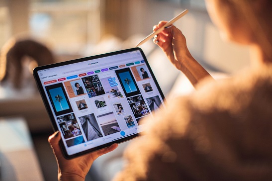 Blick &uuml;ber die Schulter einer Frau. Sie hat ein Tablet in der Hand und einen Tablet-Stift in der Hand.